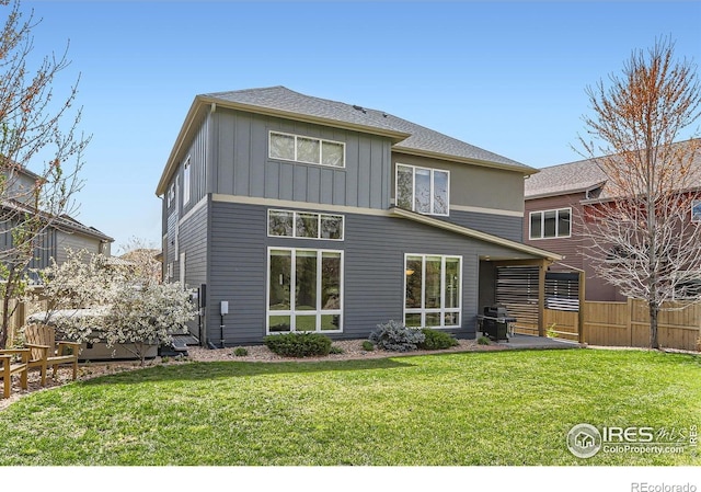 back of house featuring a lawn, fence, a patio, and board and batten siding