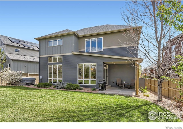 rear view of house with fence, a patio area, board and batten siding, and a yard