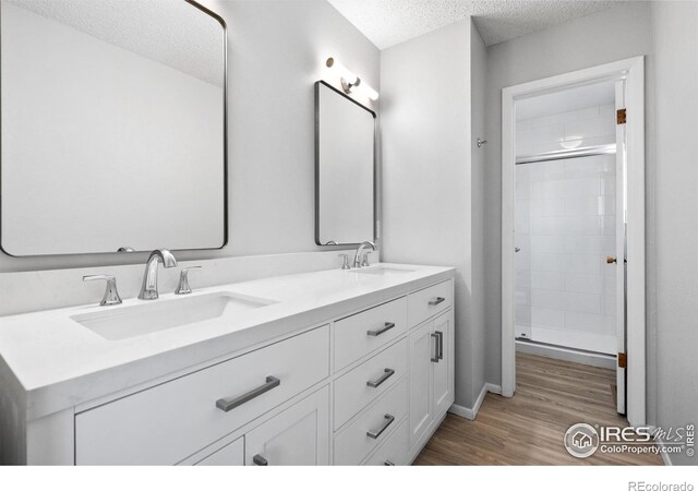 910 Sparta Dr, Lafayette, CO 80026 - bathroom featuring a textured ceiling, wood finished floors, a shower stall, and a sink