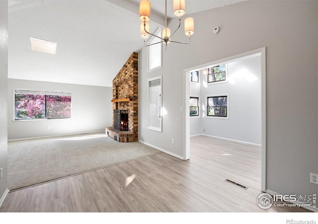 910 Sparta Dr, Lafayette, CO 80026 - unfurnished living room featuring a fireplace, a chandelier, a wealth of natural light, and wood finished floors