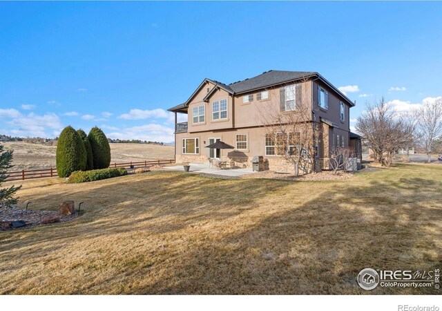 back of property with stone siding, fence, a yard, a patio, and stucco siding