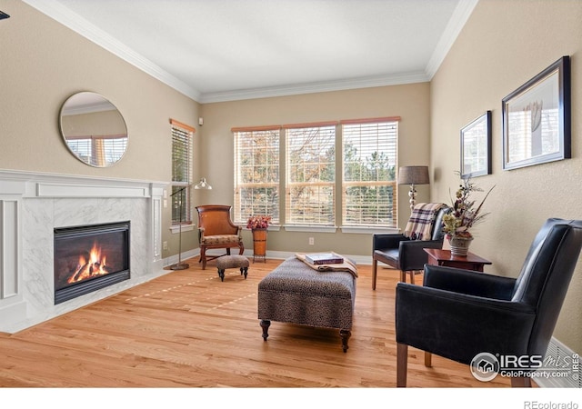 living area featuring baseboards, wood finished floors, a fireplace, and crown molding