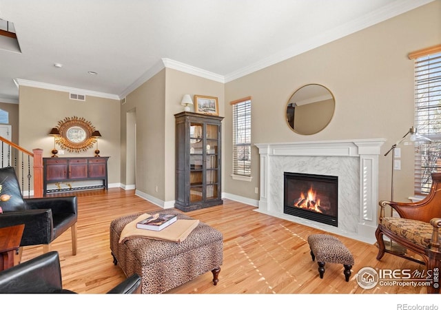 living room featuring visible vents, light wood finished floors, and ornamental molding
