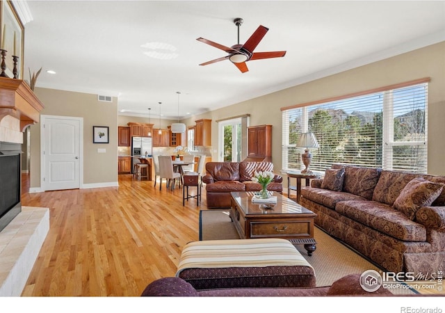 living area featuring ornamental molding, a wealth of natural light, light wood finished floors, and a ceiling fan