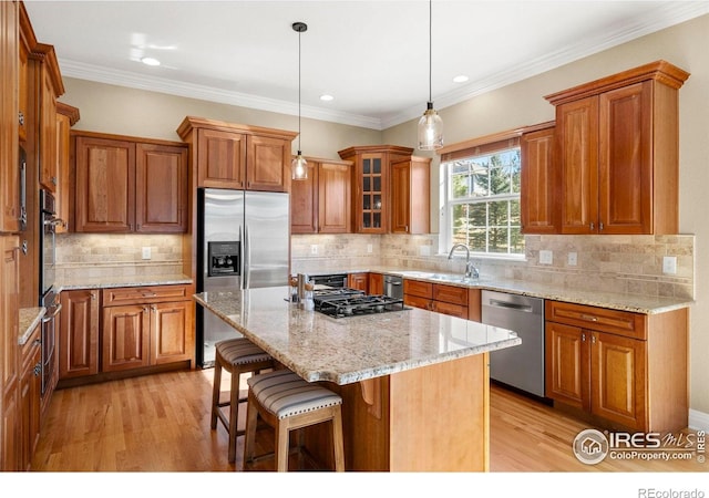 kitchen with a breakfast bar, brown cabinets, appliances with stainless steel finishes, and light wood-style flooring