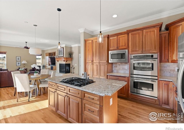 kitchen featuring tasteful backsplash, crown molding, light wood-style flooring, appliances with stainless steel finishes, and open floor plan