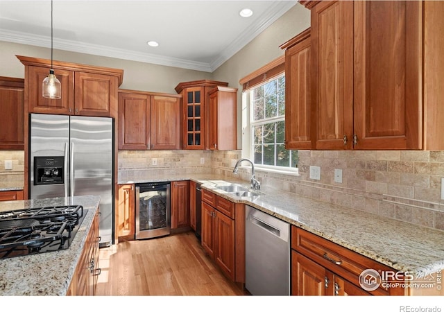 kitchen with light stone counters, a sink, beverage cooler, light wood finished floors, and appliances with stainless steel finishes