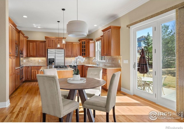 dining space featuring light wood-style floors, baseboards, and ornamental molding