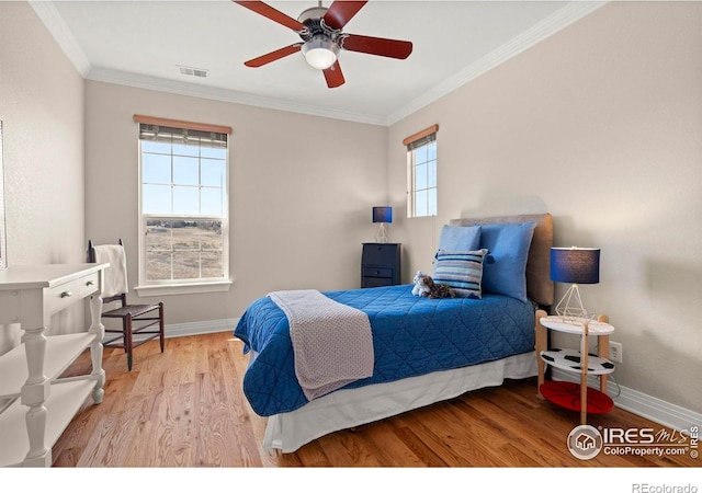bedroom featuring baseboards, wood finished floors, visible vents, and ornamental molding