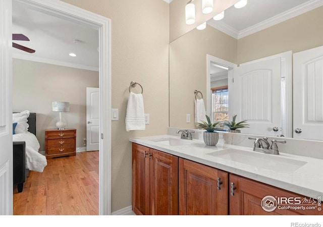 full bath featuring crown molding, wood finished floors, a sink, and double vanity