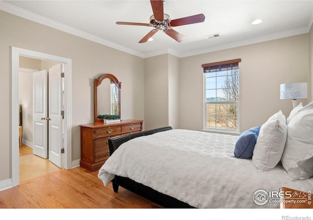 bedroom featuring baseboards, ornamental molding, visible vents, and light wood-style flooring