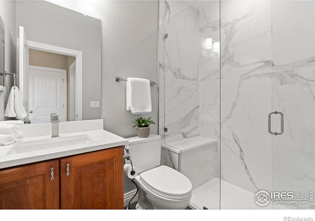 bathroom featuring a textured wall, toilet, vanity, and a marble finish shower