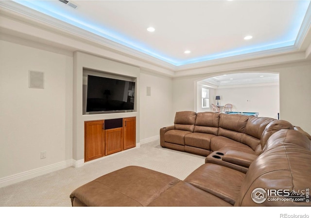 carpeted living room featuring arched walkways, a tray ceiling, ornamental molding, visible vents, and recessed lighting