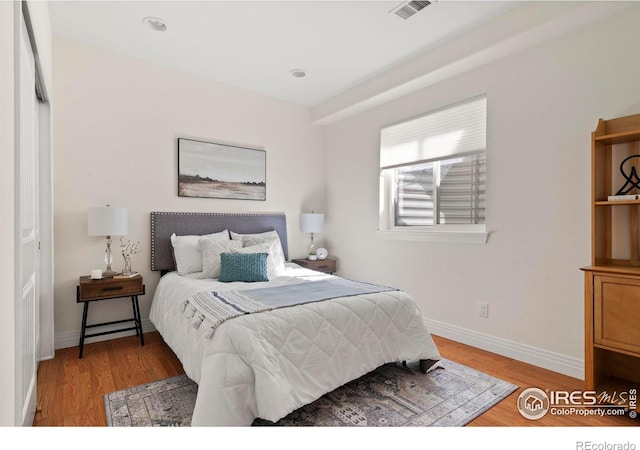 bedroom featuring baseboards, wood finished floors, and visible vents