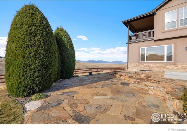 view of patio / terrace featuring a mountain view, a balcony, and fence