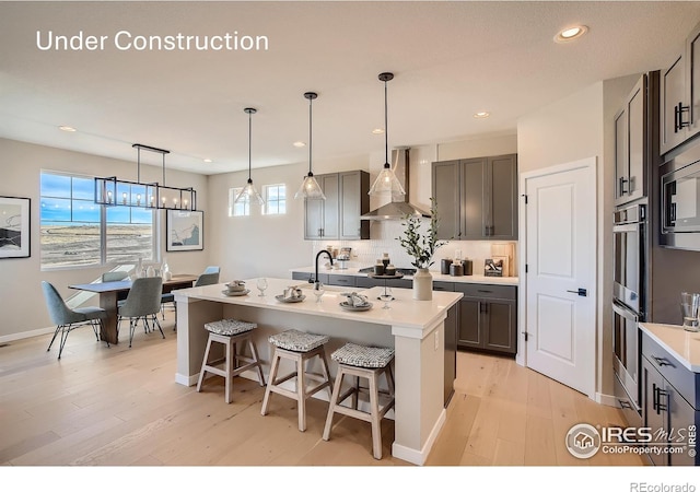 2719 Crystal Spgs, Longmont, CO 80503 - kitchen featuring wall chimney range hood, a breakfast bar area, light wood finished floors, healthy amount of natural light, and recessed lighting