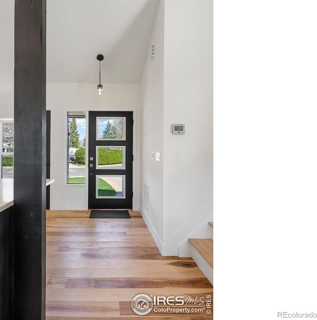 entryway featuring stairway, lofted ceiling, light wood-style floors, and visible vents