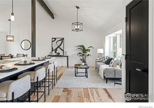 living room featuring light wood finished floors, vaulted ceiling with beams, and a notable chandelier