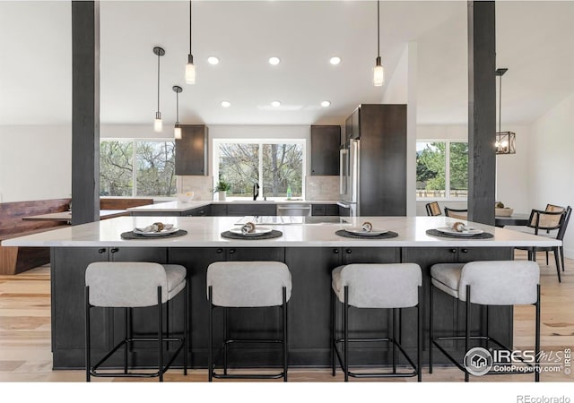 kitchen with light wood finished floors, light countertops, a breakfast bar area, and a healthy amount of sunlight