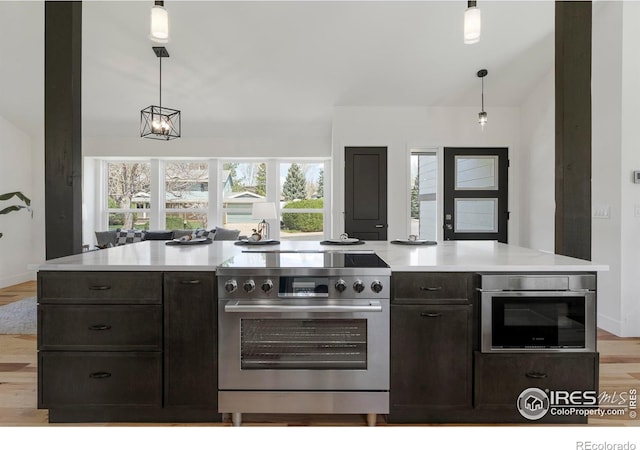kitchen featuring light wood-type flooring, pendant lighting, stainless steel appliances, light countertops, and baseboards
