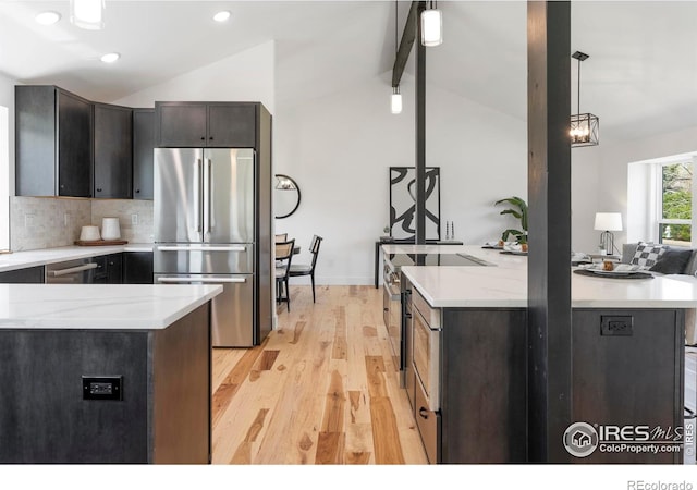 kitchen with decorative backsplash, appliances with stainless steel finishes, vaulted ceiling with beams, and light wood-style flooring