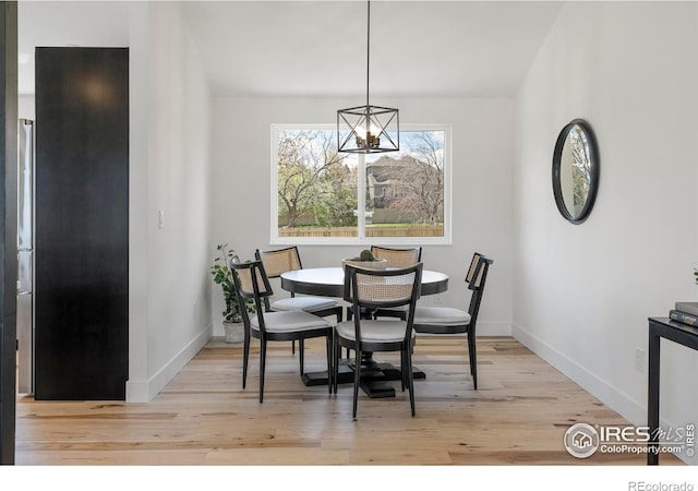 dining space with baseboards, a chandelier, and wood finished floors
