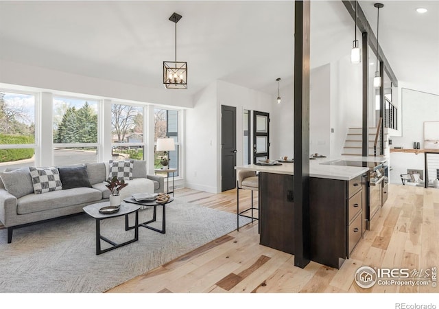 living area featuring light wood-style flooring, baseboards, and stairway