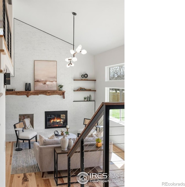 living room featuring a wealth of natural light, a glass covered fireplace, wood finished floors, and a high ceiling