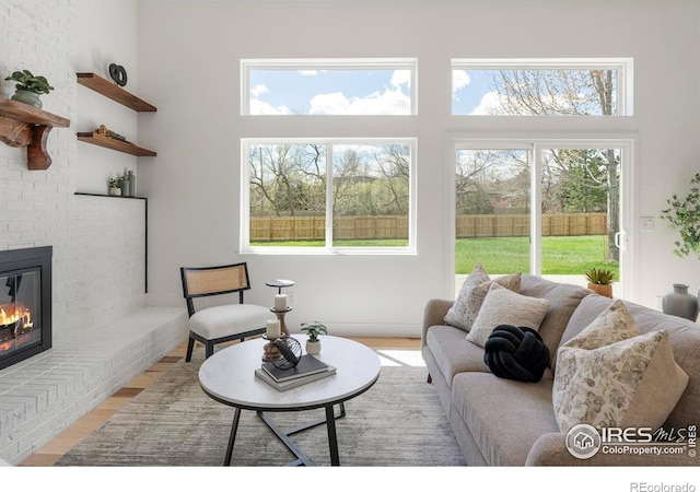 living room featuring a fireplace, light wood-style floors, a wealth of natural light, and a high ceiling