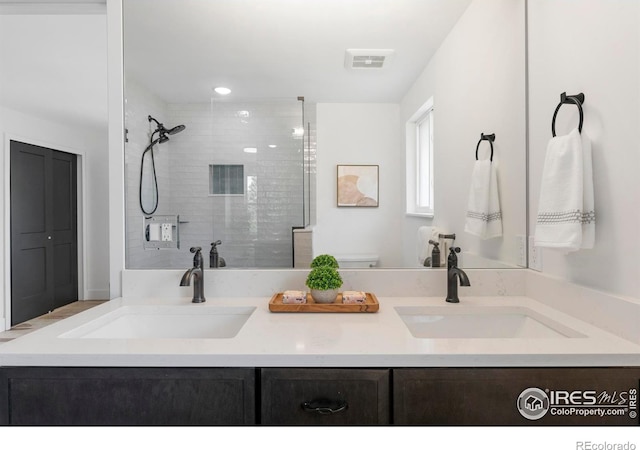 full bath with a tile shower, visible vents, a sink, and double vanity