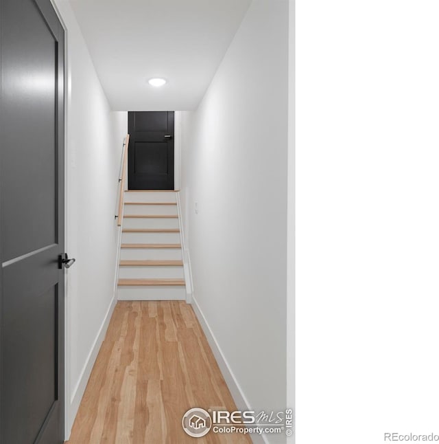 corridor featuring stairway, baseboards, and light wood-style flooring