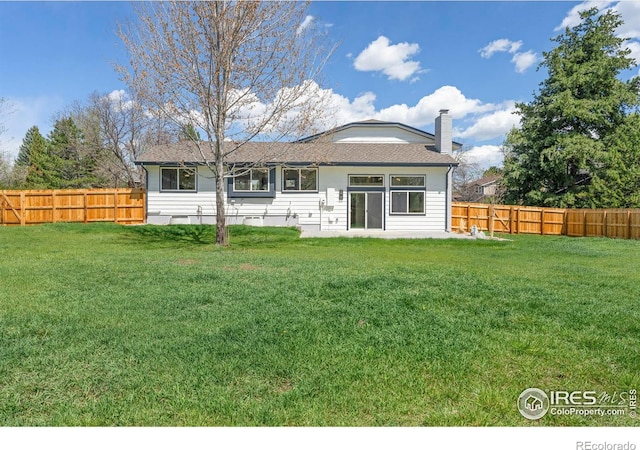 back of property with a fenced backyard, a chimney, and a yard