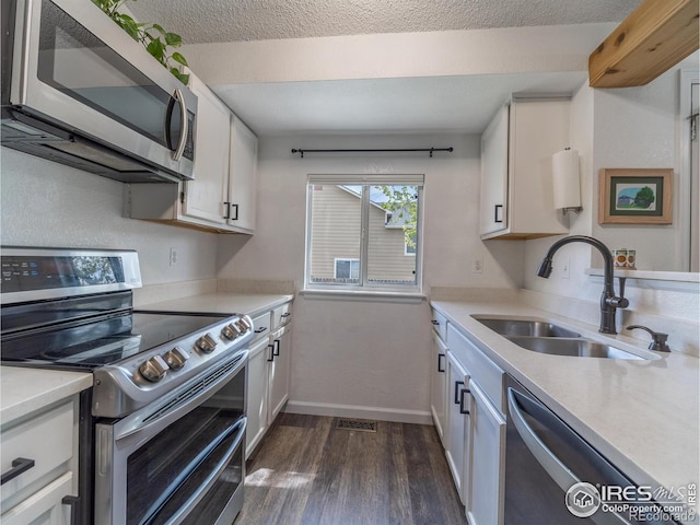 13146 Raritan Ct, Westminster, CO 80234 - kitchen with appliances with stainless steel finishes, dark wood finished floors, a sink, light countertops, and white cabinetry