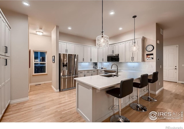 1356 Golden Eagle Way, Louisville, CO 80027 - kitchen with a sink, light wood-style floors, a breakfast bar, a peninsula, and appliances with stainless steel finishes