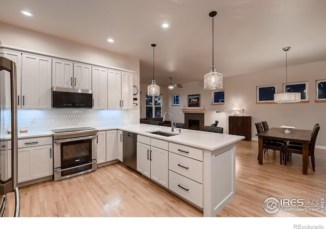 1356 Golden Eagle Way, Louisville, CO 80027 - kitchen with stainless steel appliances, a sink, decorative backsplash, a peninsula, and light wood-style flooring