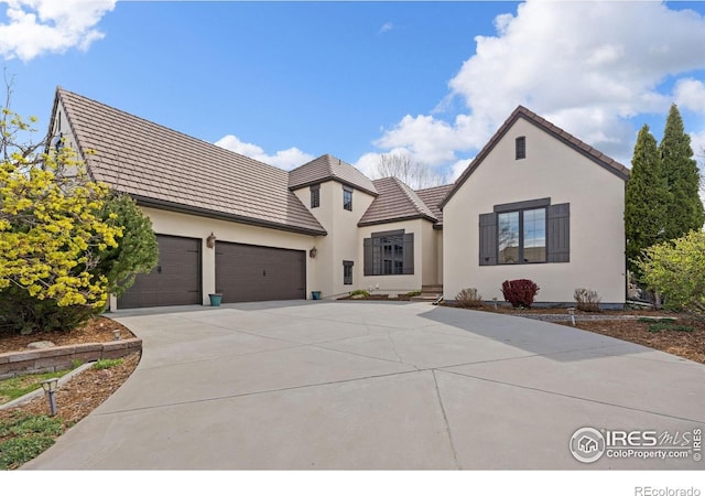 895 Owl Grove Pl, Loveland, CO 80537 - french country home featuring a garage, a tile roof, driveway, and stucco siding