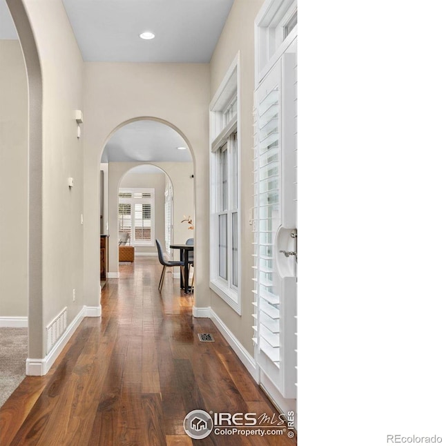 895 Owl Grove Pl, Loveland, CO 80537 - hallway featuring arched walkways, dark wood-style flooring, visible vents, and baseboards