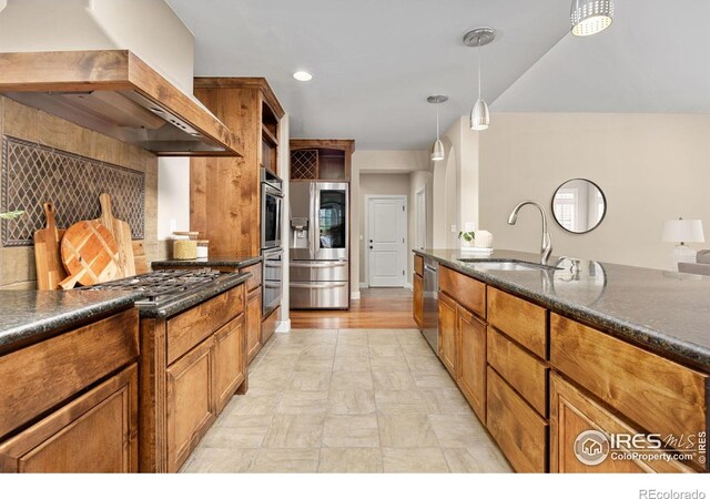 895 Owl Grove Pl, Loveland, CO 80537 - kitchen featuring wall chimney range hood, a sink, hanging light fixtures, brown cabinets, and appliances with stainless steel finishes