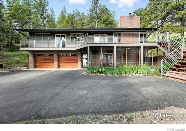 74 Sky Trail Rd, Boulder, CO 80302 - view of front of home with driveway, brick siding, a chimney, stairs, and a garage