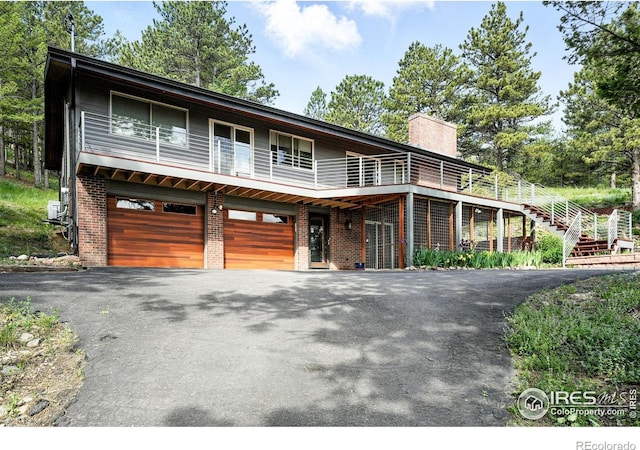 74 Sky Trail Rd, Boulder, CO 80302 - view of front of home with driveway, a chimney, brick siding, and a garage
