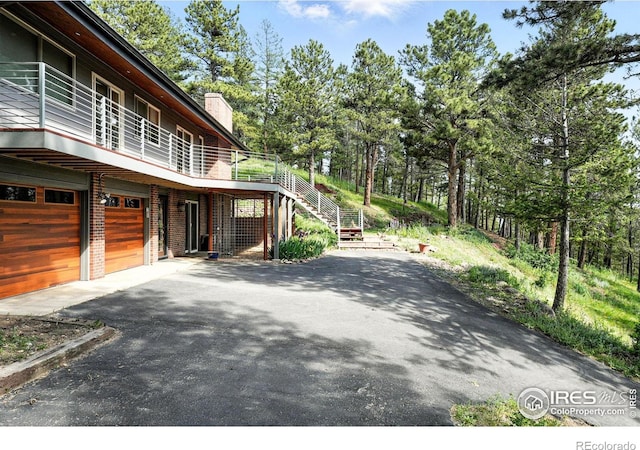 74 Sky Trail Rd, Boulder, CO 80302 - view of home's exterior with asphalt driveway, a garage, a chimney, stairs, and a wooden deck