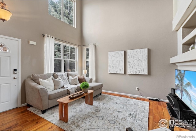 living area featuring visible vents, wood finished floors, and a towering ceiling