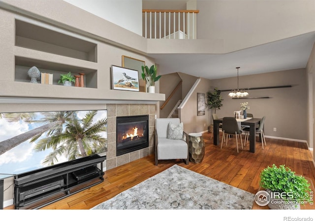 living room with a fireplace, baseboards, a chandelier, and hardwood / wood-style floors