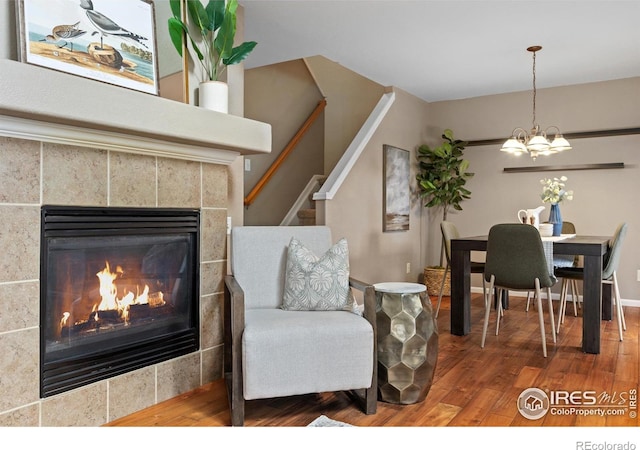 interior space featuring a fireplace, wood finished floors, an inviting chandelier, and stairs