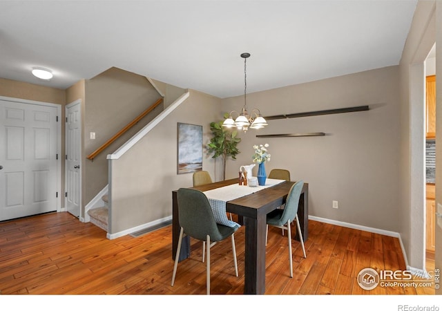 dining area featuring a chandelier, baseboards, stairs, and wood-type flooring