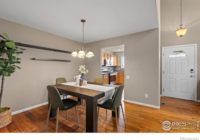 dining space featuring baseboards, a notable chandelier, and light wood-style flooring