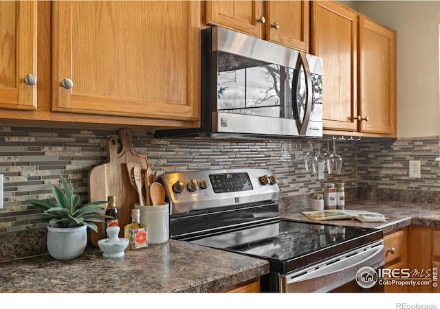 kitchen with stainless steel appliances, decorative backsplash, and dark countertops