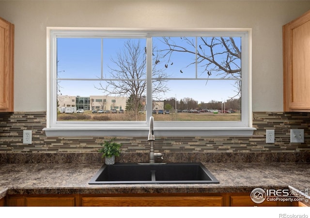 details with backsplash, dark countertops, and a sink