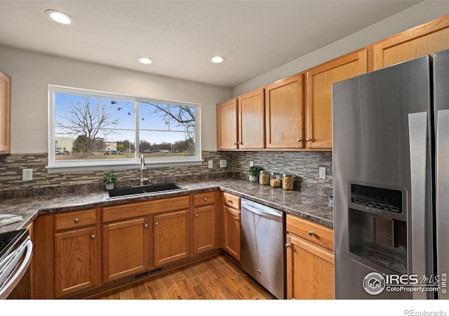 kitchen with light wood-style flooring, a sink, tasteful backsplash, visible vents, and appliances with stainless steel finishes