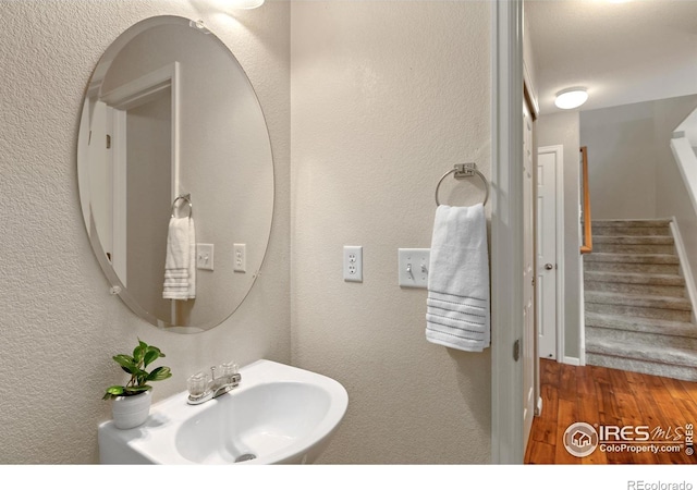 bathroom with wood finished floors, a textured wall, and a sink